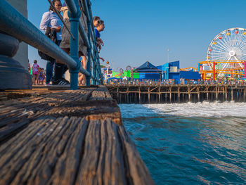 People on pier at beach against sky