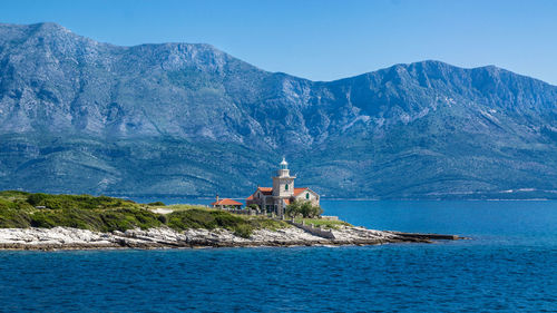 Lighthouse amidst sea and buildings against sky