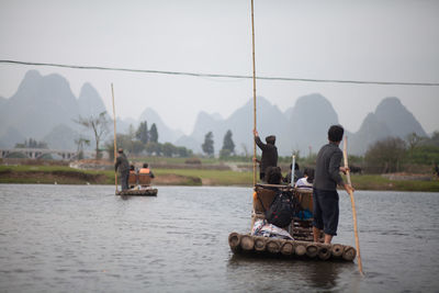 Boatmen rowing wooden raft in river