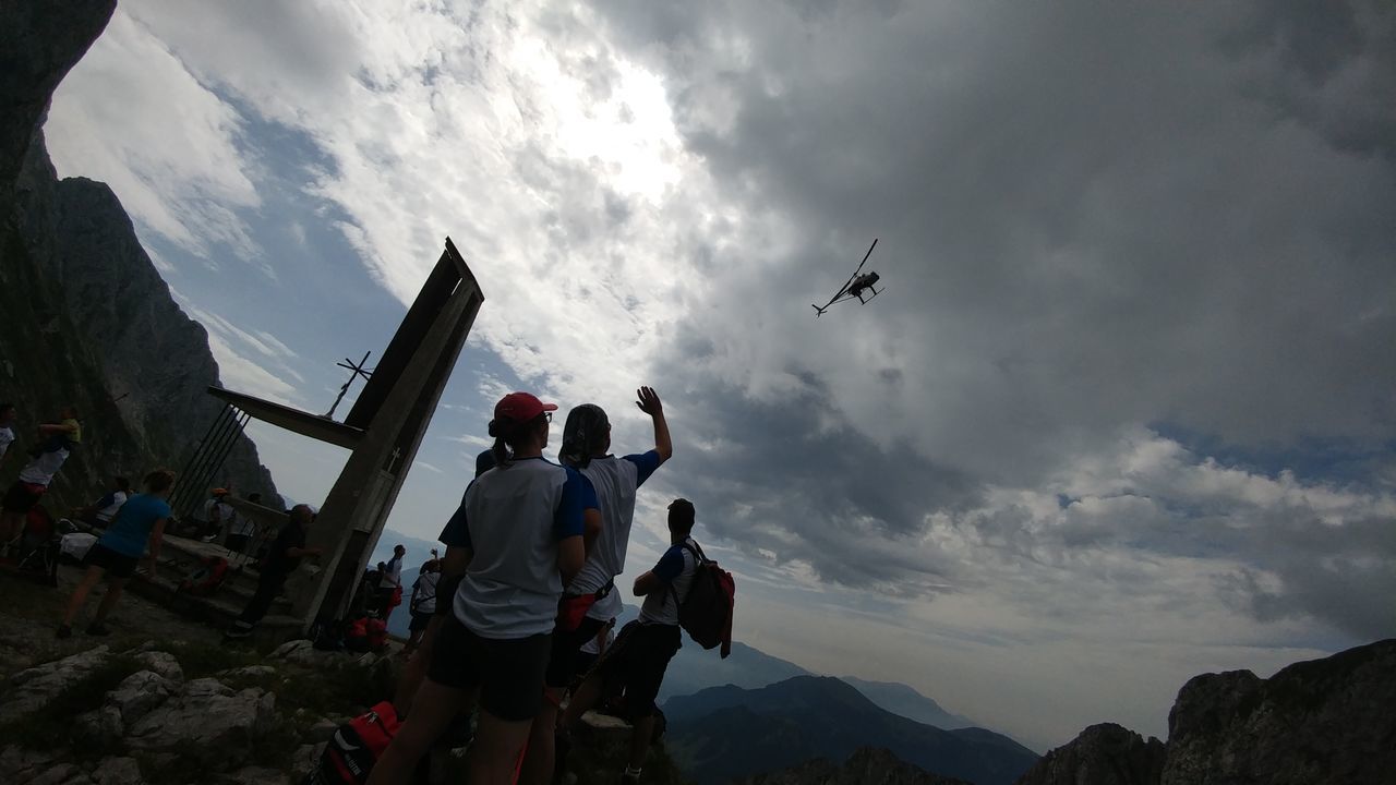 LOW ANGLE VIEW OF MEN AGAINST MOUNTAIN