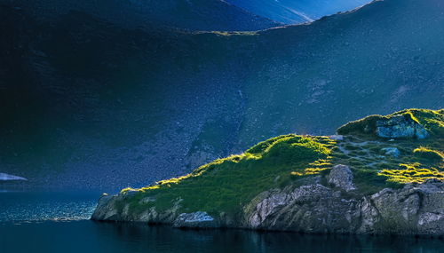 Scenic view of sea and mountains against blue sky