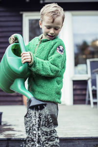 Boy using watering can in yard