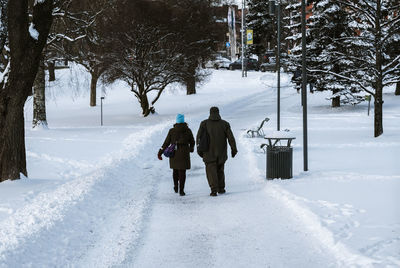 Rear view of men walking on snow field