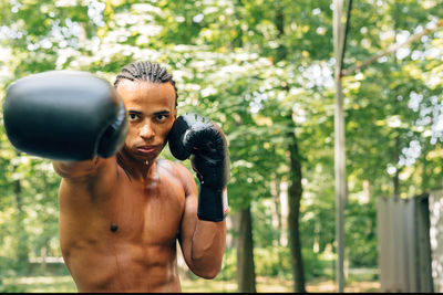 Portrait of shirtless man boxing on street