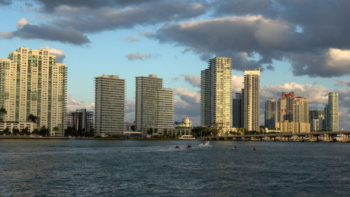 Sea by modern buildings against sky