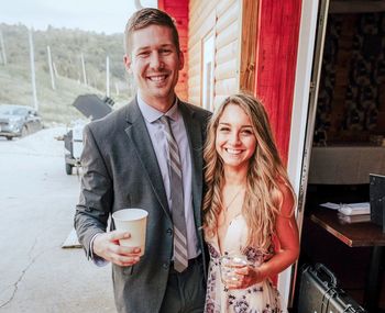 Portrait of smiling couple holding coffee cup by window