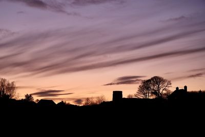 Silhouette trees and buildings against sky at sunset