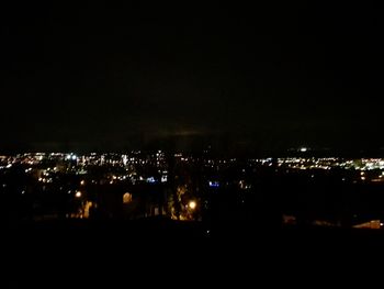 Illuminated cityscape against sky at night