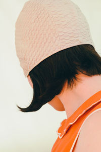 Close-up side view of woman wearing swimming cap against white background