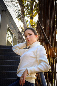 Portrait of young woman standing against building