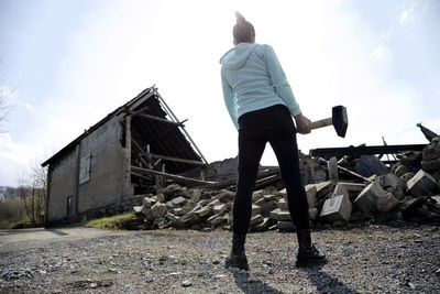 Woman holding hammer on road during sunny day