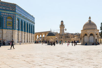 Group of people in front of historic building against clear sky