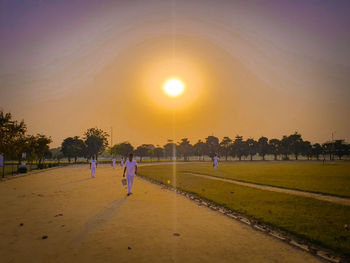 People on street against sky during sunset