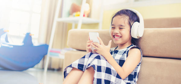 Close-up of cute girl using mobile phone at home