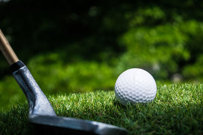 Close-up of golf stick and ball on field