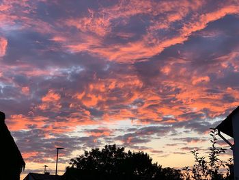 Low angle view of silhouette trees against dramatic sky