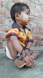 Full length of boy sitting against wall