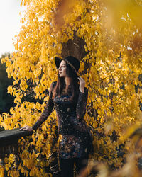 Woman standing by yellow flowering plants during autumn