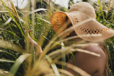 Portrait of young woman wearing hat amidst grass