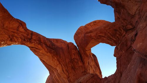 Low angle view of rock formation against clear blue sky