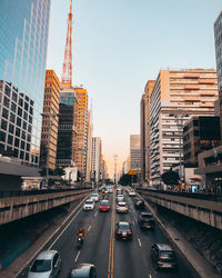 Traffic on road amidst buildings in city against sky
