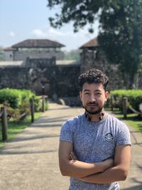 Portrait of young man standing against built structure