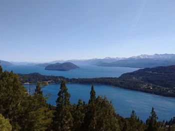 Scenic view of sea and mountain against clear blue sky