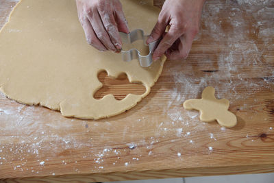 Cropped hands of chef cutting dough with pastry cutter at table