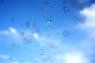 Low angle view of bubbles against blue sky