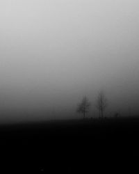 Silhouette trees on field against clear sky