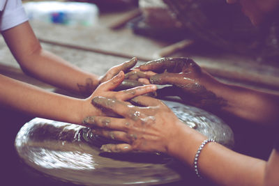 Cropped hands making pot on pottery wheel