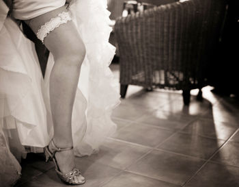 Low section of bride wearing garter belt on floor