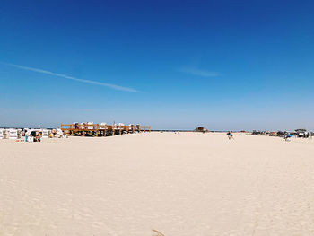 Group of people on beach against clear blue sky
