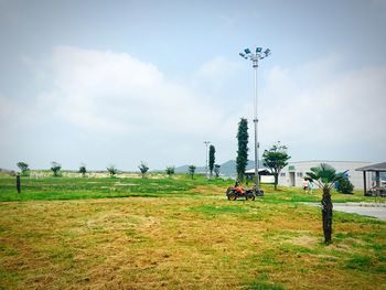 Trees on grassy field against cloudy sky