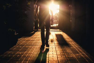 Low section view of man walking in alley at sunrise