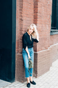 Full length of woman standing against brick wall