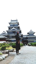 Rear view of man standing outside temple against building