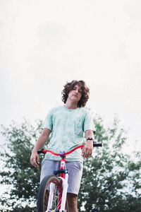 Low angle portrait of man riding bicycle against clear sky