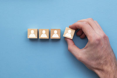 Cropped hand of person holding toy blocks on blue background