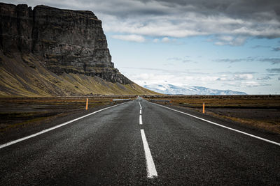 Road leading towards mountain against sky