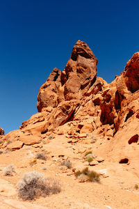 Low angle view of rock formations against clear blue sky