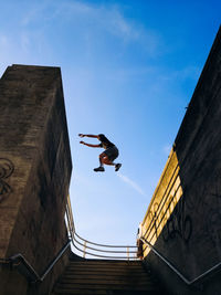 Low angle view of man jumping against sky