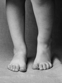 Low section of baby walking on floor, legs barefoot 