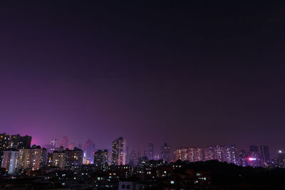 Illuminated cityscape against sky at night
