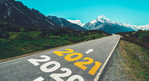 Text on road by mountains against sky