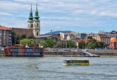 View of buildings at waterfront against cloudy sky