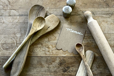 Directly above shot of wooden utensils with menu on table