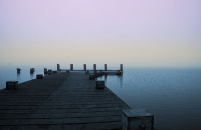 Wooden jetty in sea against clear sky