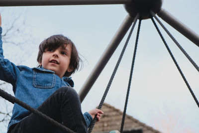 Low angle view of boy standing against sky