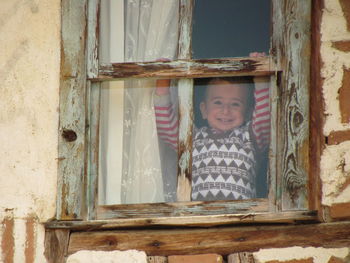 Low angle view of baby boy seen through window